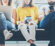 3 people sitting on a couch using devices