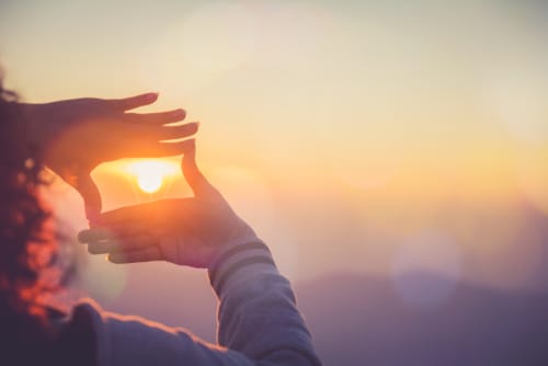 someone putting their hands in a box around the sun in the sky