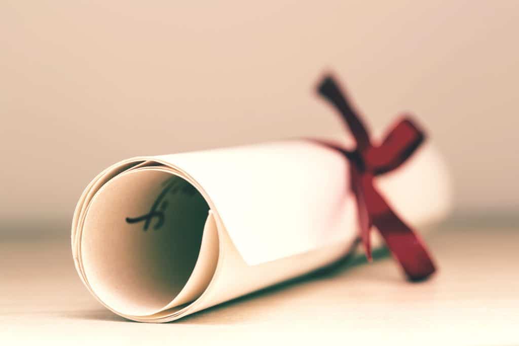 a degree certificate rolled and tied with a red ribbon