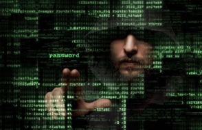 a hooded man standing behind a virtual wall of code