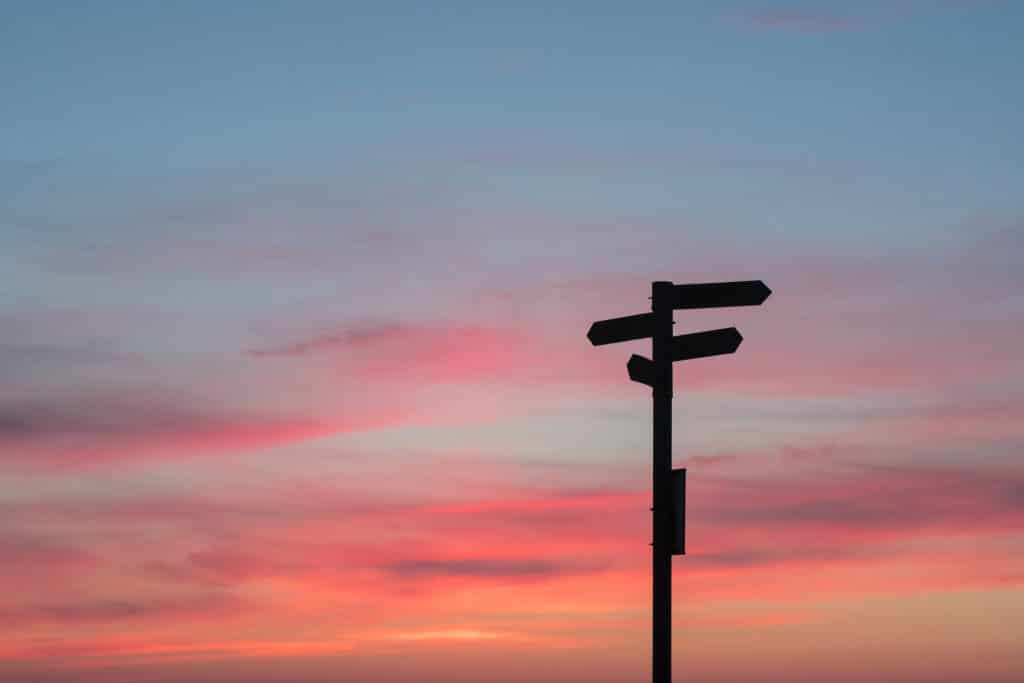 silhouette of a muli-directional street sign against a dusk sky