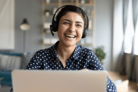 a woman at a computer wearing a headset and laughing