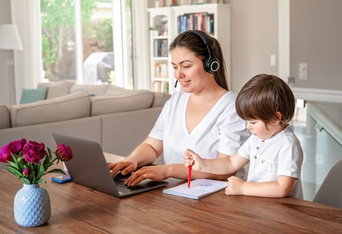 a mum working at home with her child next to her