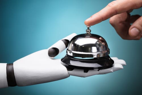 a hand pressing a desk bell held by a robot