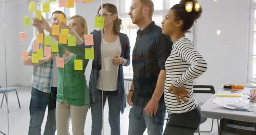a group working with sticky notes on a glass wall