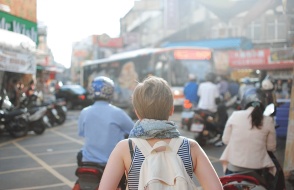 a girl with a backpack walking down a busy road in a foreign country