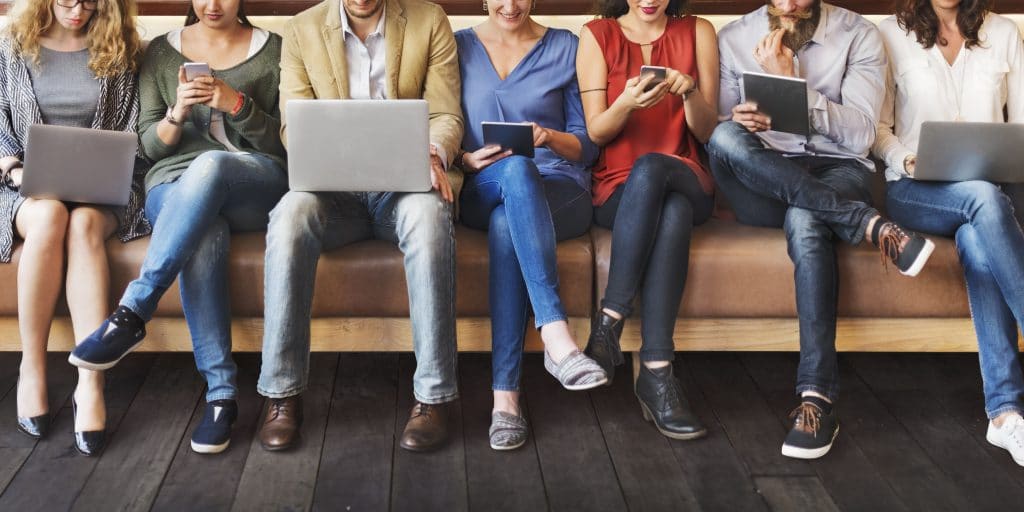 7 people on a bench seat using various devices