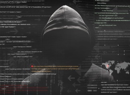 a hooded person behind a wall of computer code
