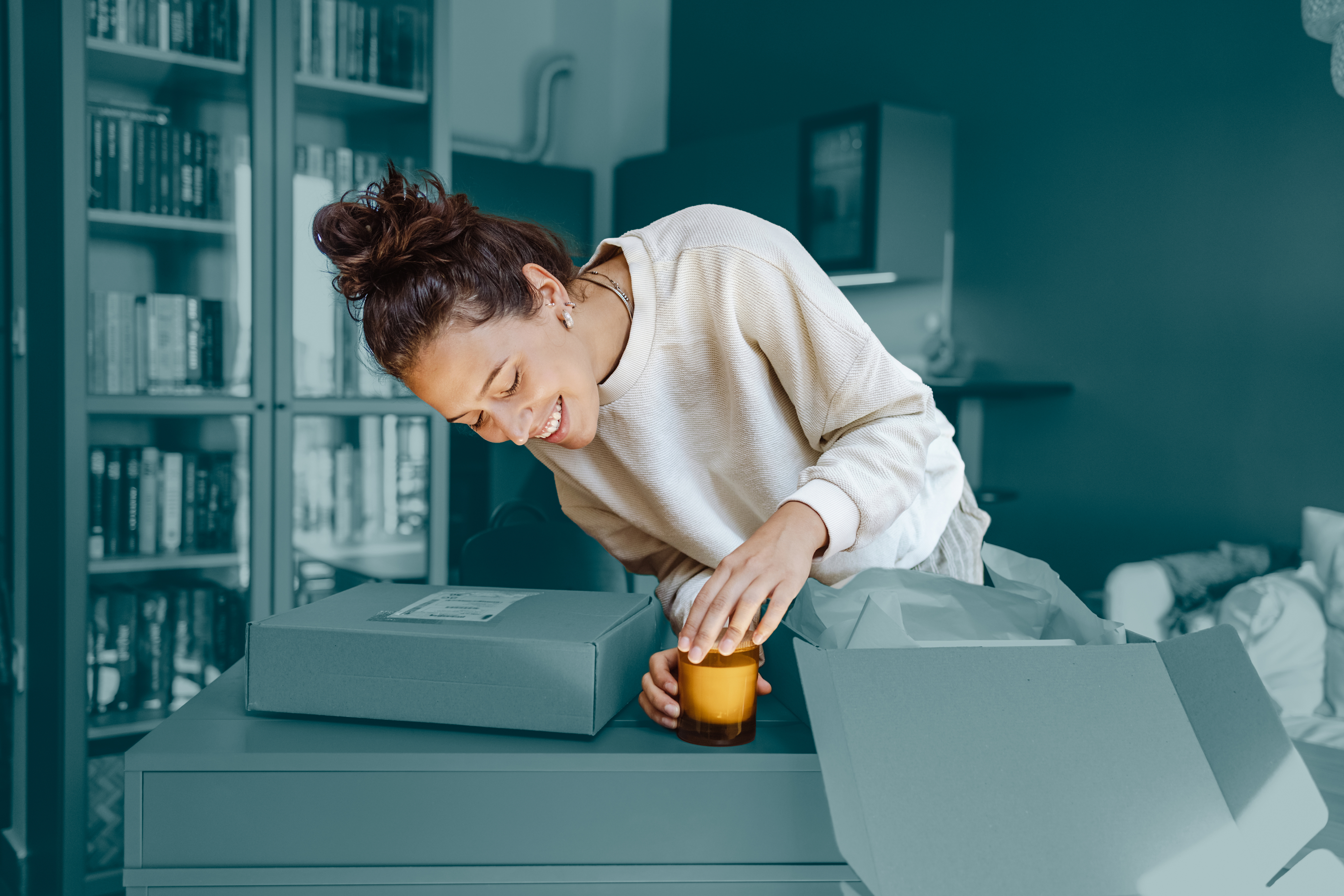 Woman preparing a yellow candle to ship, surrounded by parcel boxes