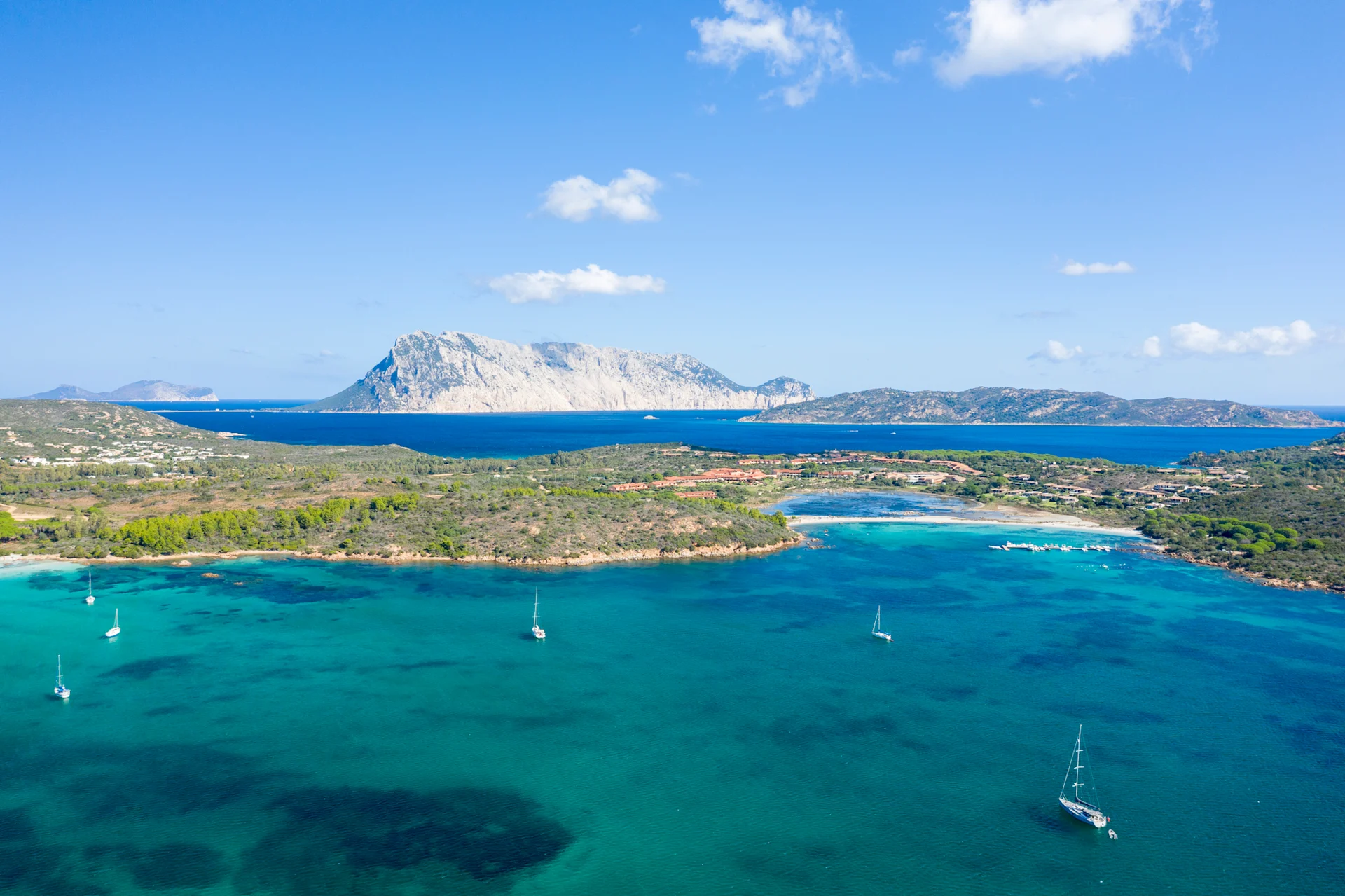 Wide image of Spiaggia Salina Bamba beach, with the surrounding waters dotted with boats.
