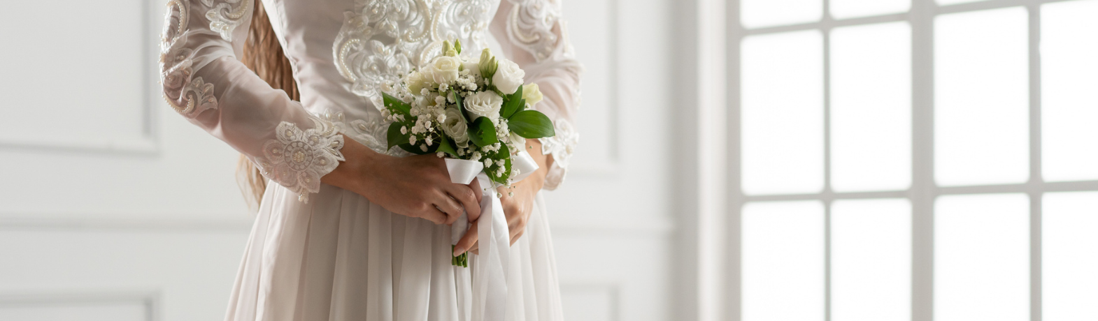 Bride wearing a sequined white wedding dress with long sleeves, holding a white bridal bouquet.
