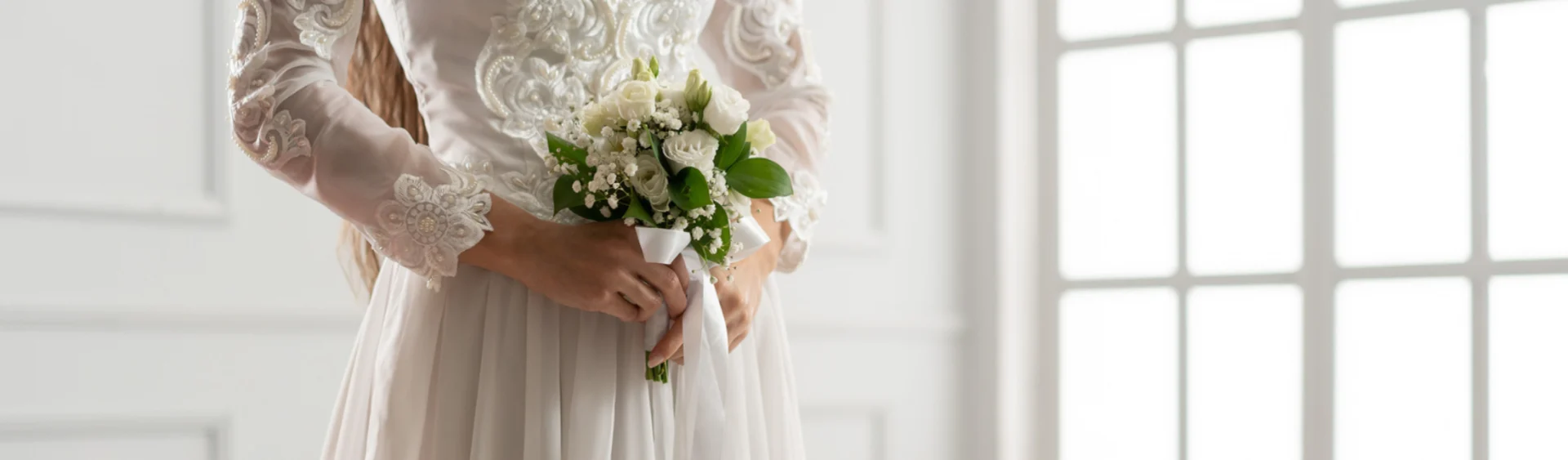 Bride wearing a sequined white wedding dress with long sleeves, holding a white bridal bouquet.