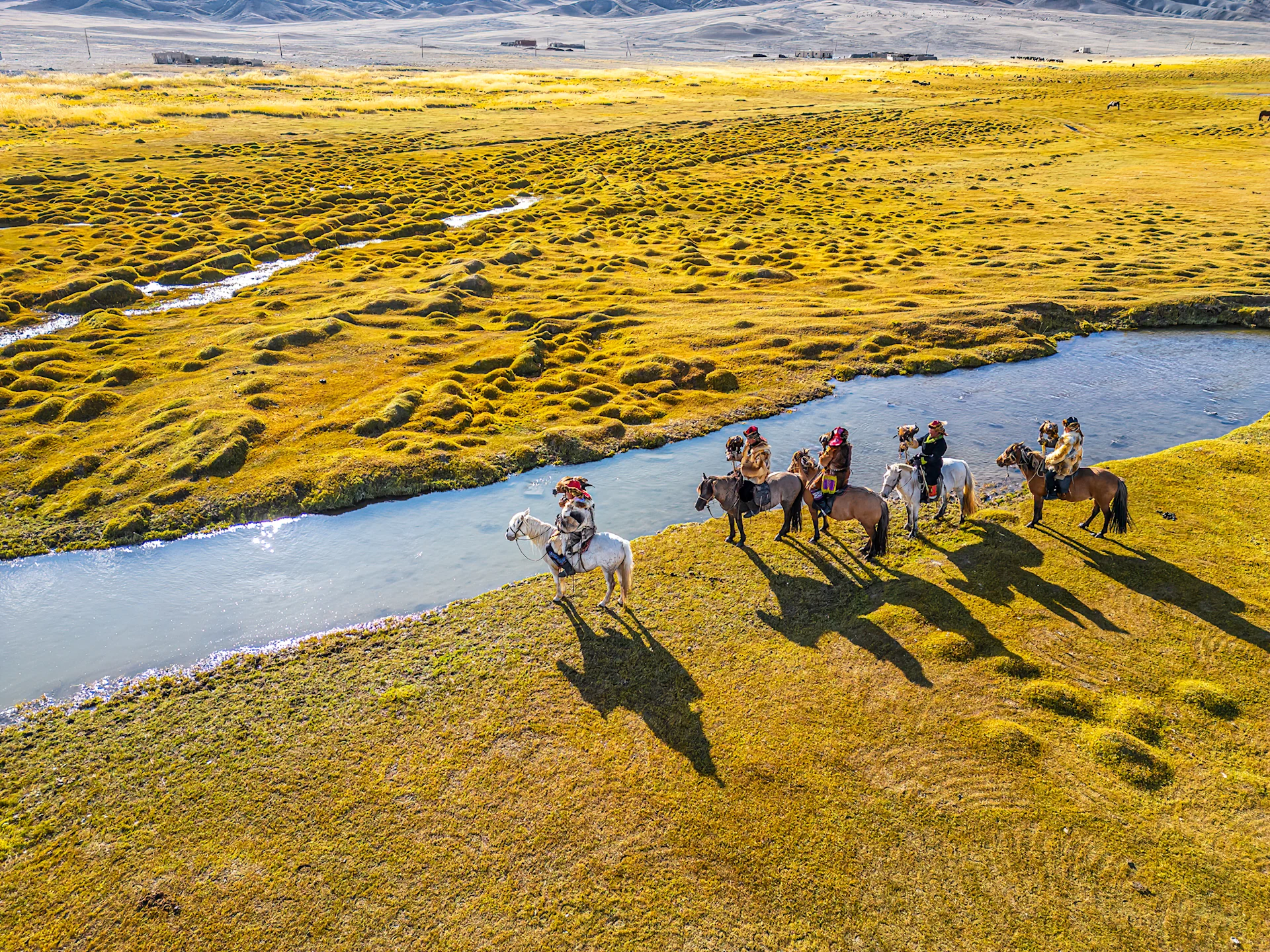 Riders on horseback on a marsh in Mongolia.