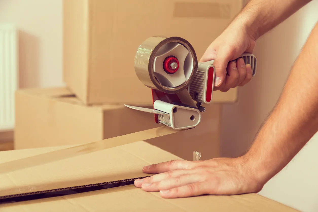 Man taping up a box with brown parcel tape
