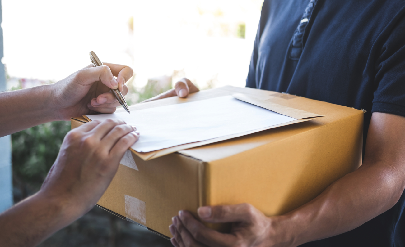 Delivery man at door while person signs for parcel