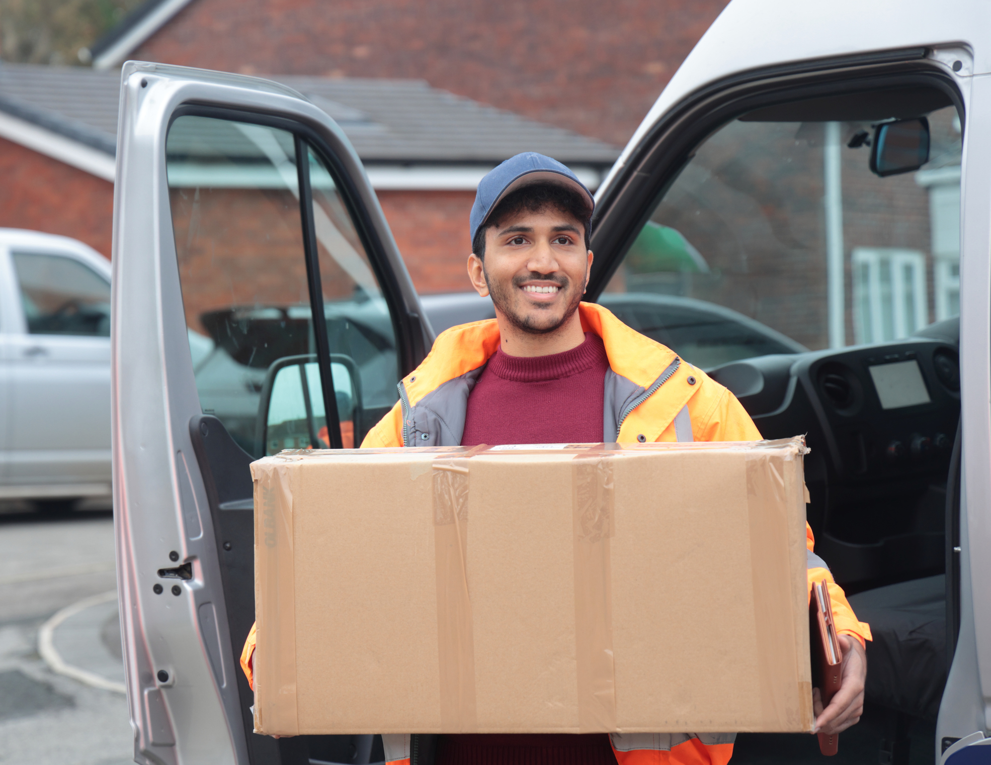 Man smiling whilst delivering a large parcel.