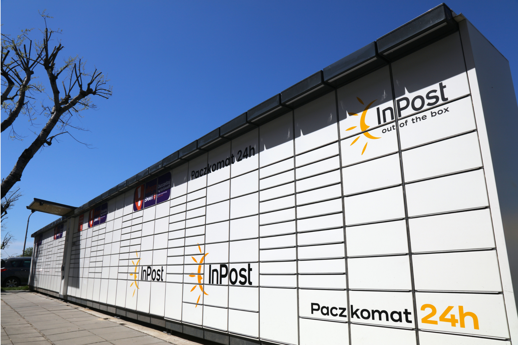 Long row of white InPost lockers outside on in front of clear blue sky