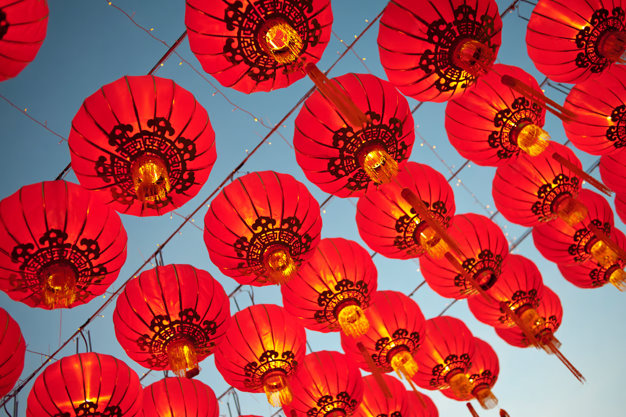 Red Chinese lanterns on strings against a night sky at dusk