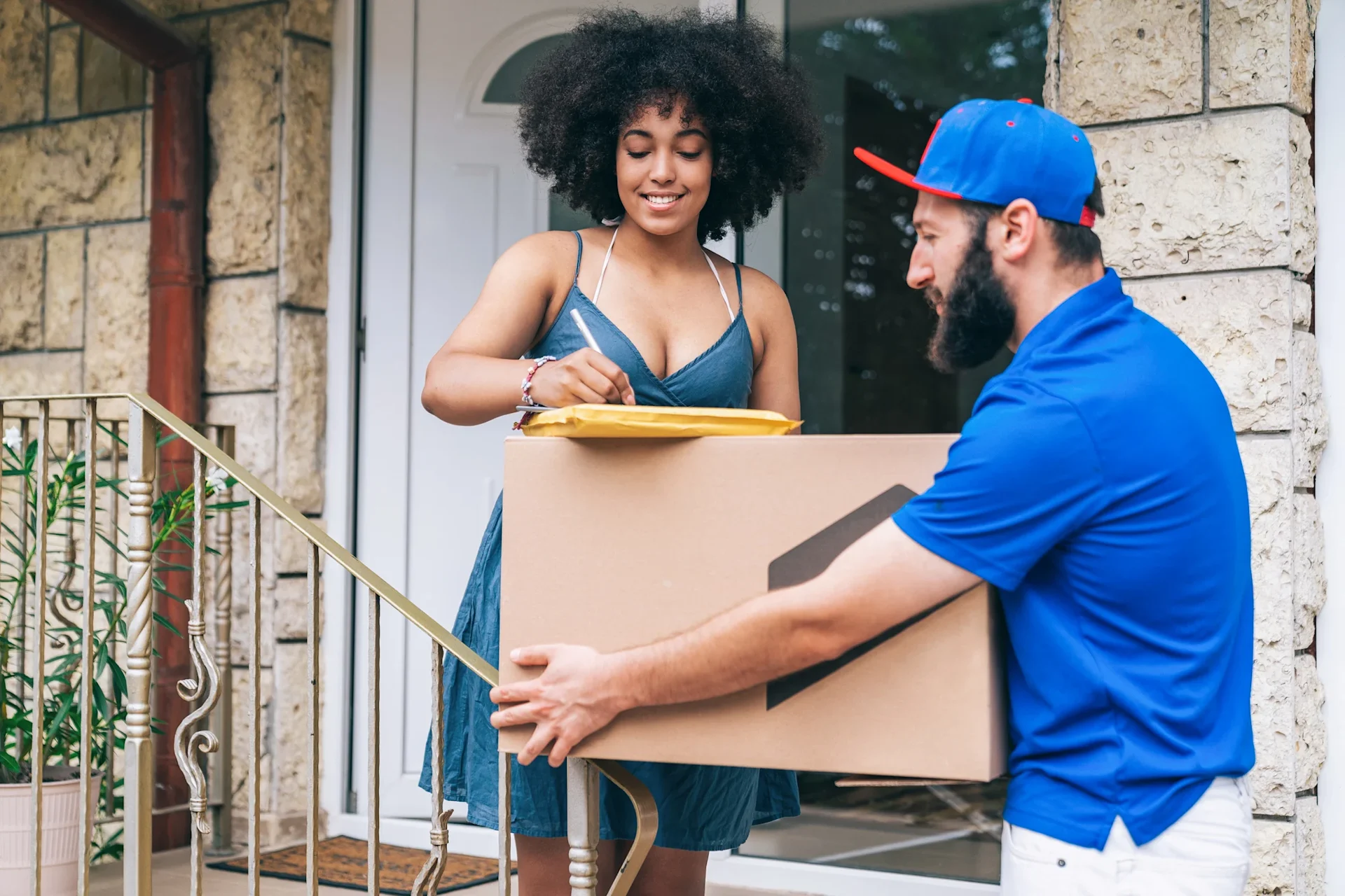 Courier picking up a large parcel from woman at the front door