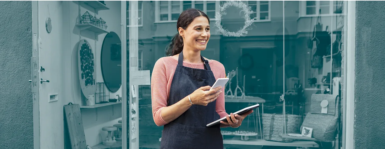 Woman at store with clipboard and mobile phone smiling with blue background
