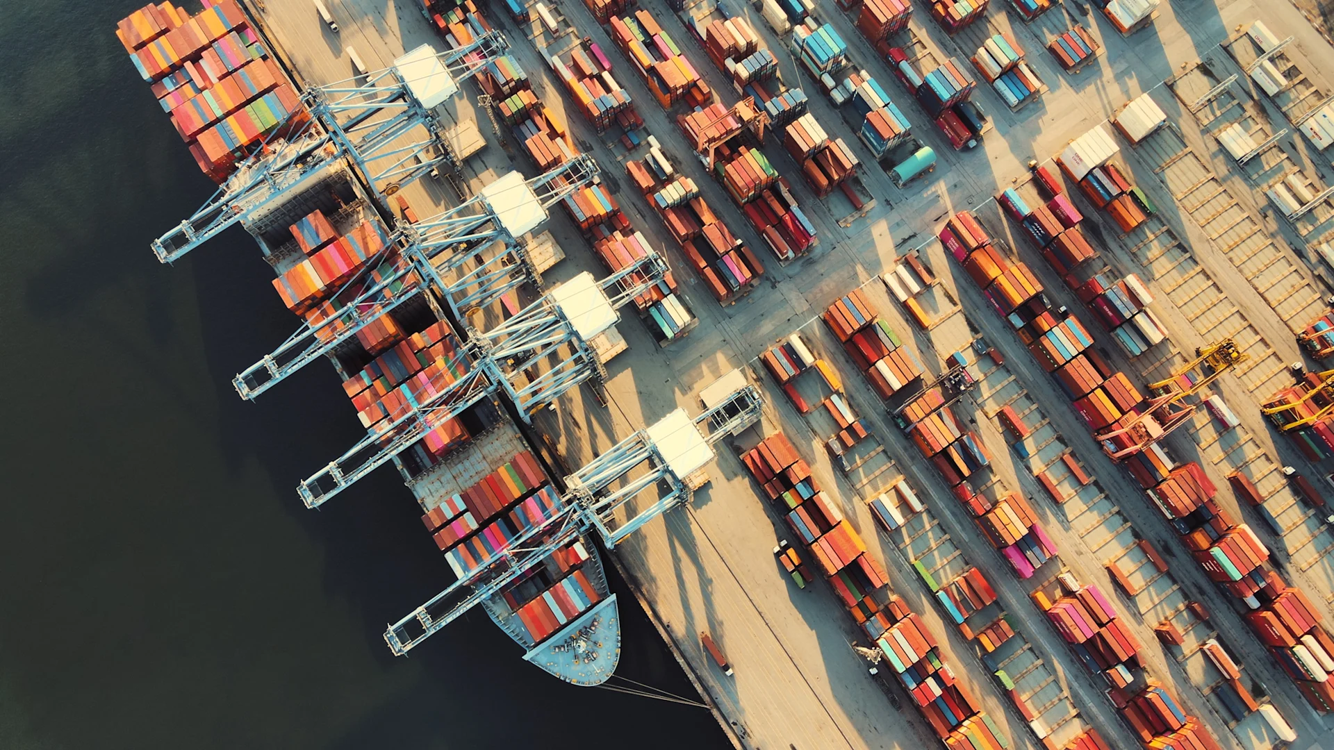 Top-down view of cargo ship docked shipping cranes and coastal industrial harbor in Singapore with export containers and urban backdrop at tanjong pagar, Singapore.