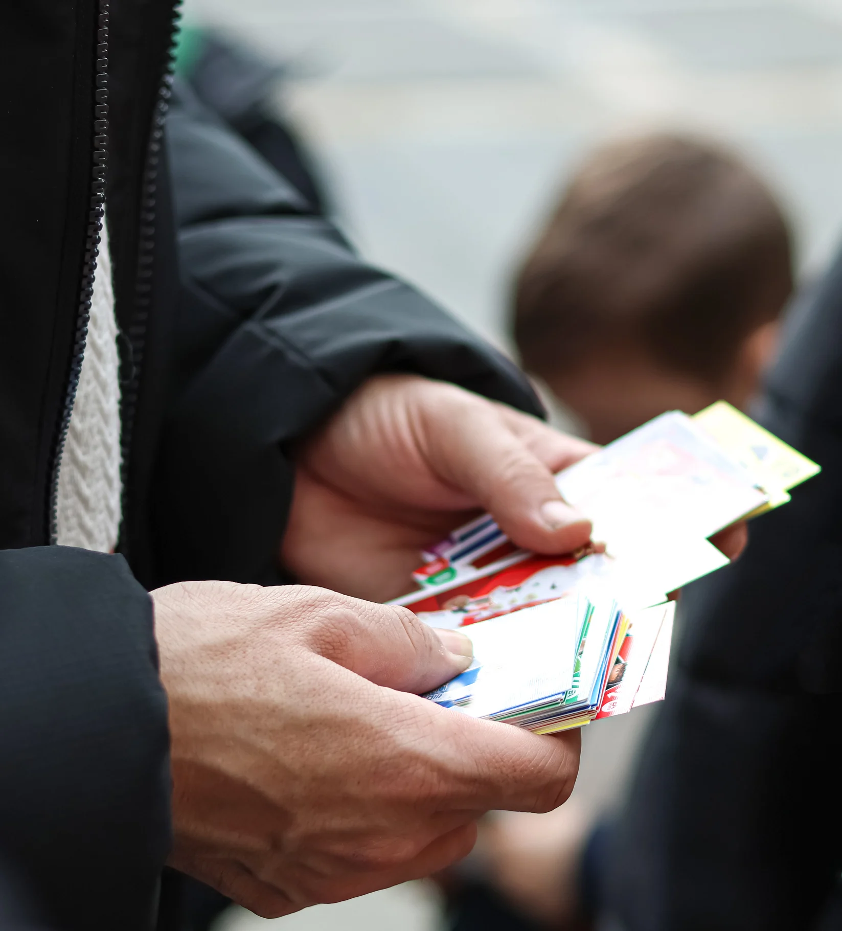 Male presenting person's hands shuffling between unidentifiable trading cards.