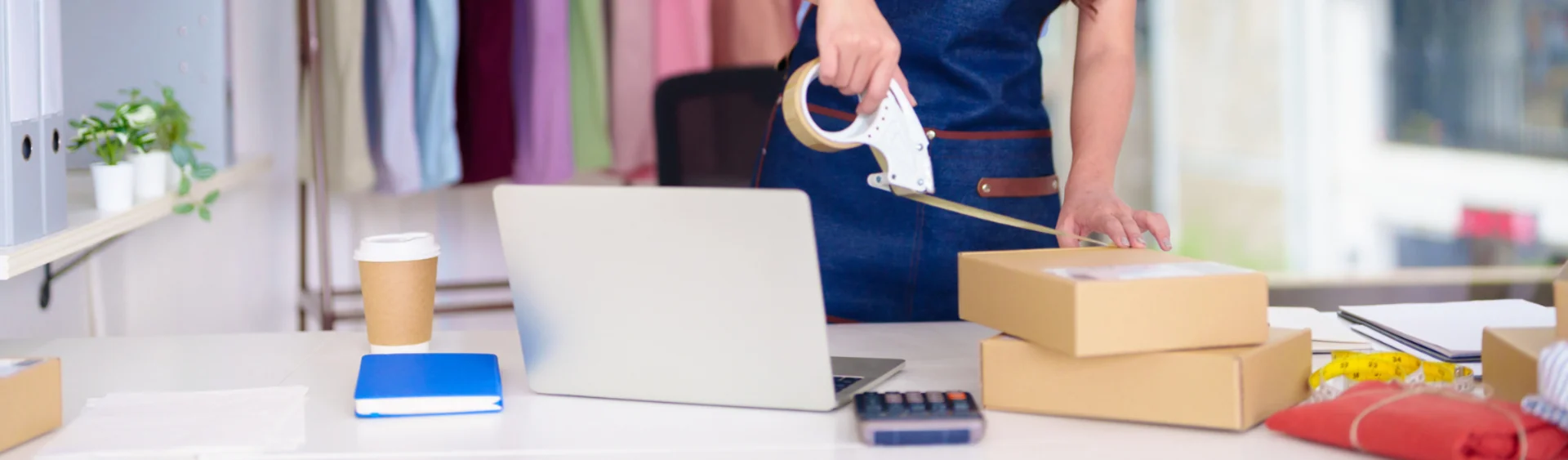Person taping a parcel boxed closed, surrounded by packaging items