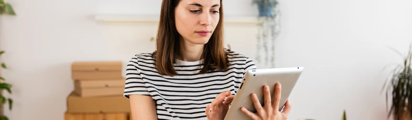 Woman using her iPad with parcel boxes behind her.