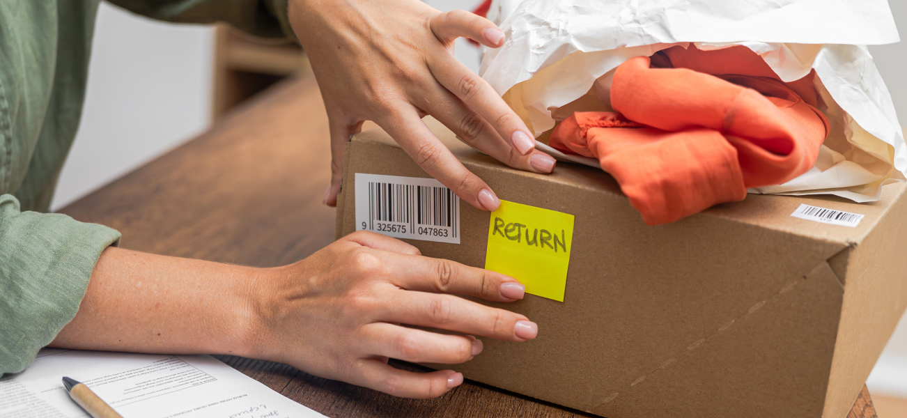 A woman's hands placing a 'Return' post-it note on a cardboard box