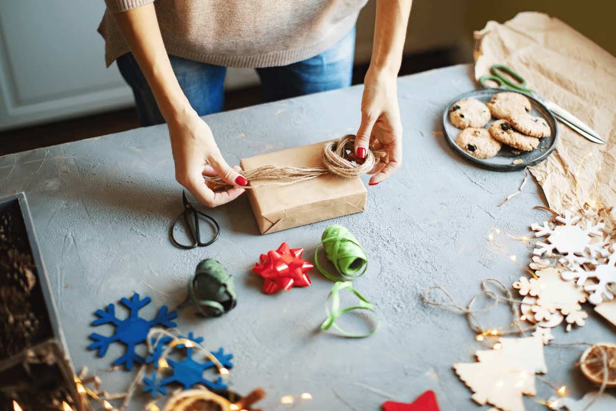 Woman wrapping Christmas parcel on desk