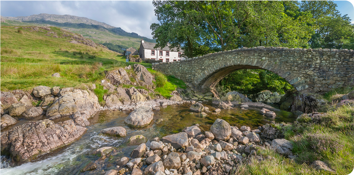 Scenic view of a house across a stream and a bridge.