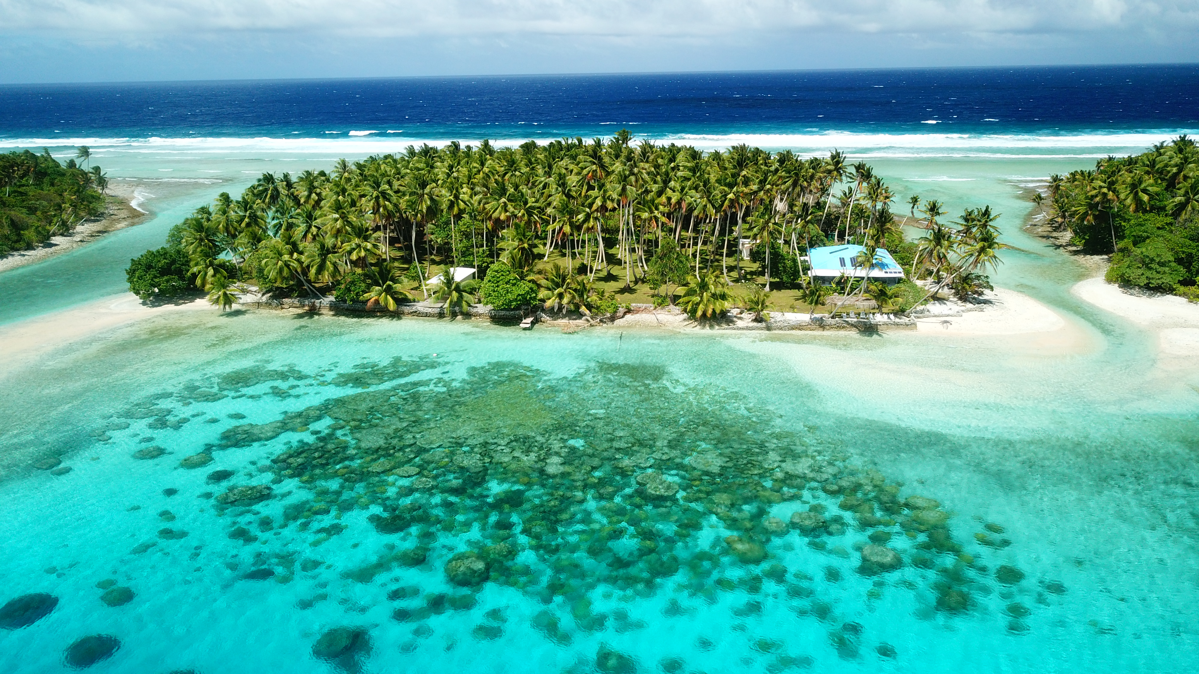 Small green islands surrounded by water - a couple of beachside houses in Marshall Islands