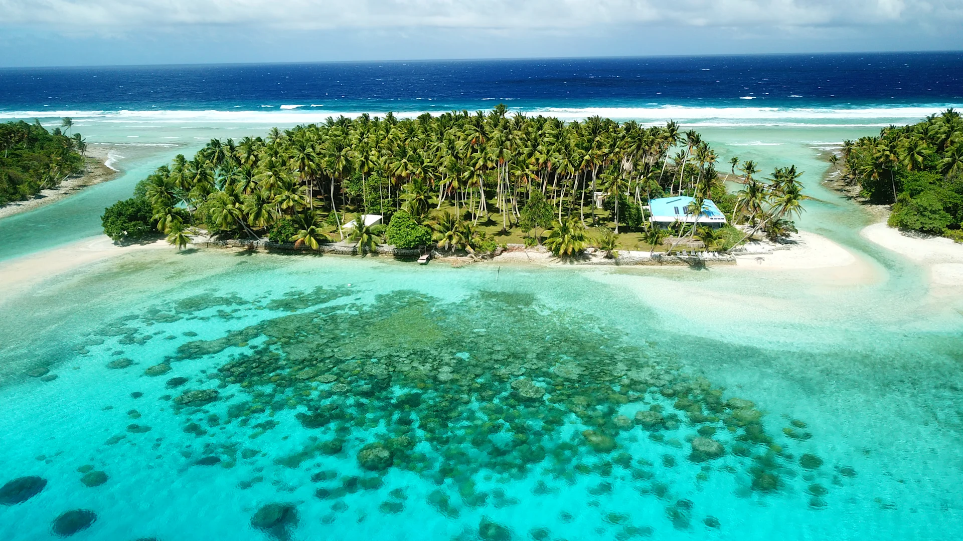 Small green islands surrounded by water - a couple of beachside houses in Marshall Islands