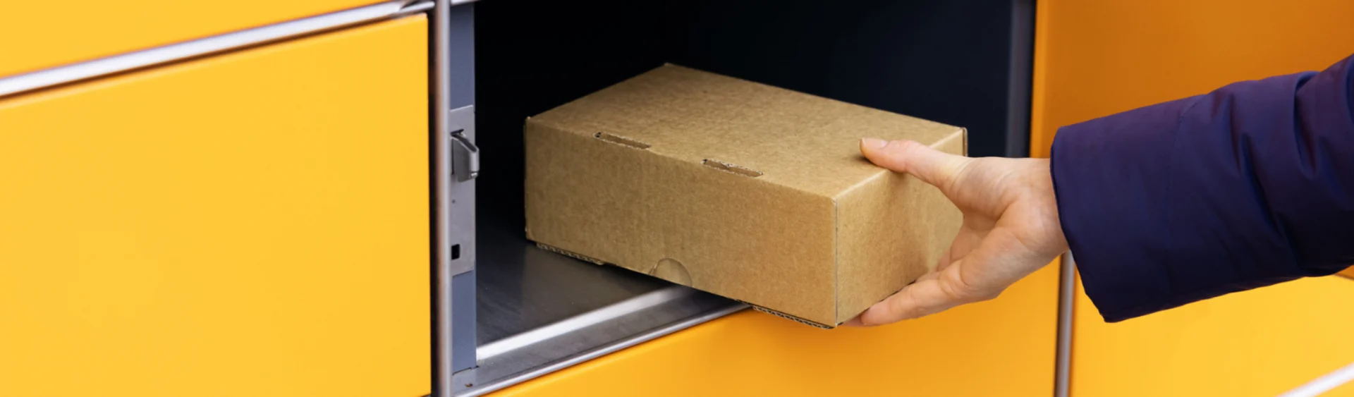 Hands drops parcel into yellow locker container.