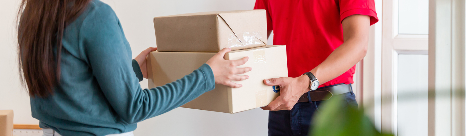 Delivery driver in red shirt handing parcel to customer
