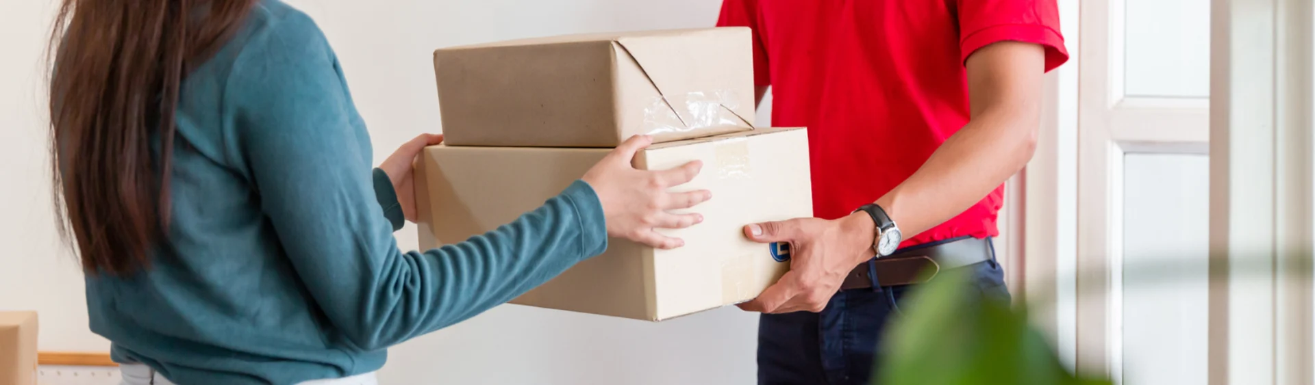 Delivery driver in red shirt handing parcel to customer