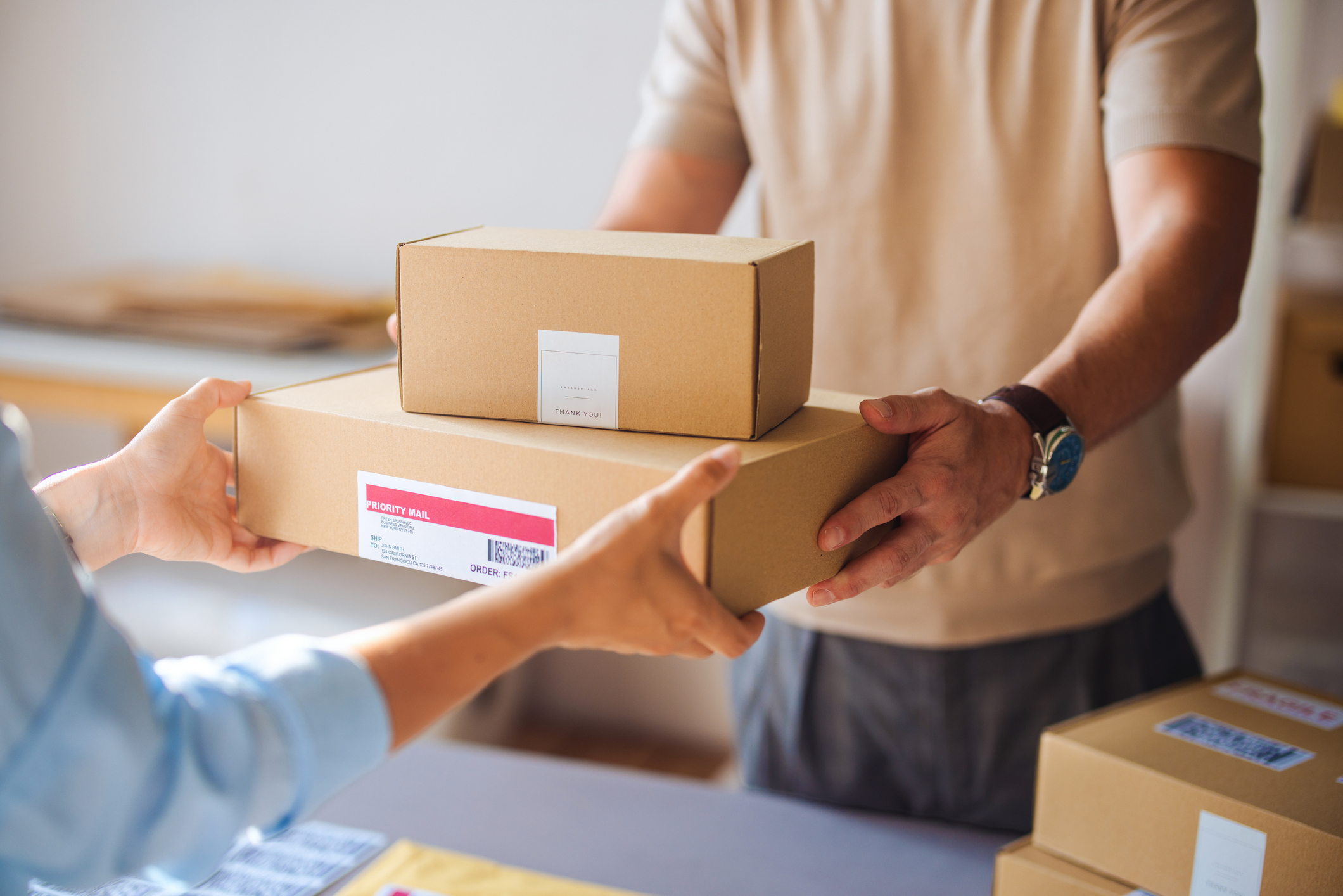 Two sets of hands exchanging a small stack of parcels.