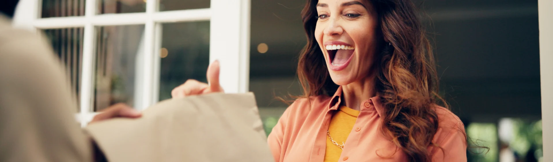 Smiling woman receiving parcel at her front door.