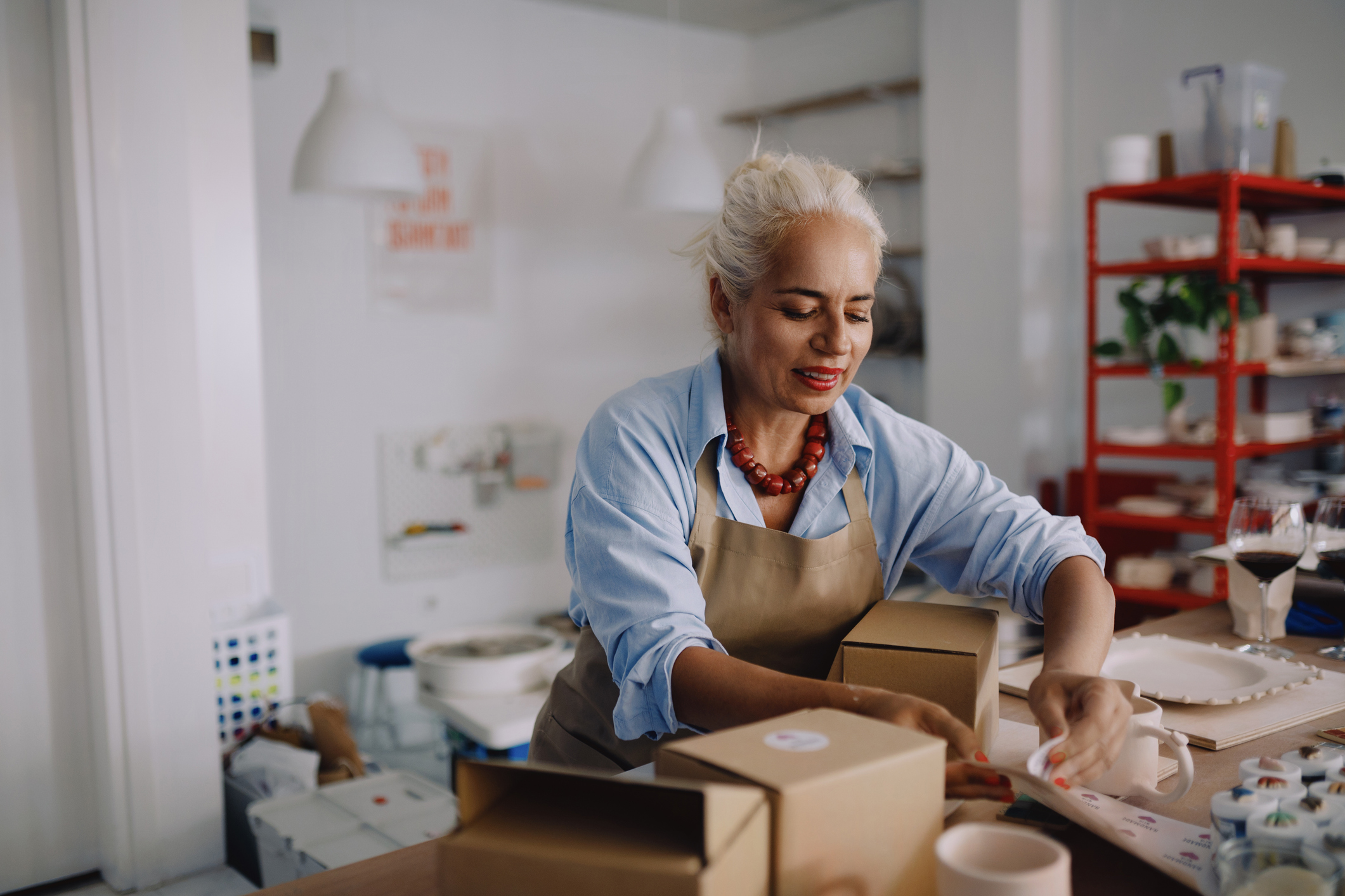 Female presenting person packs boxes for her small business.