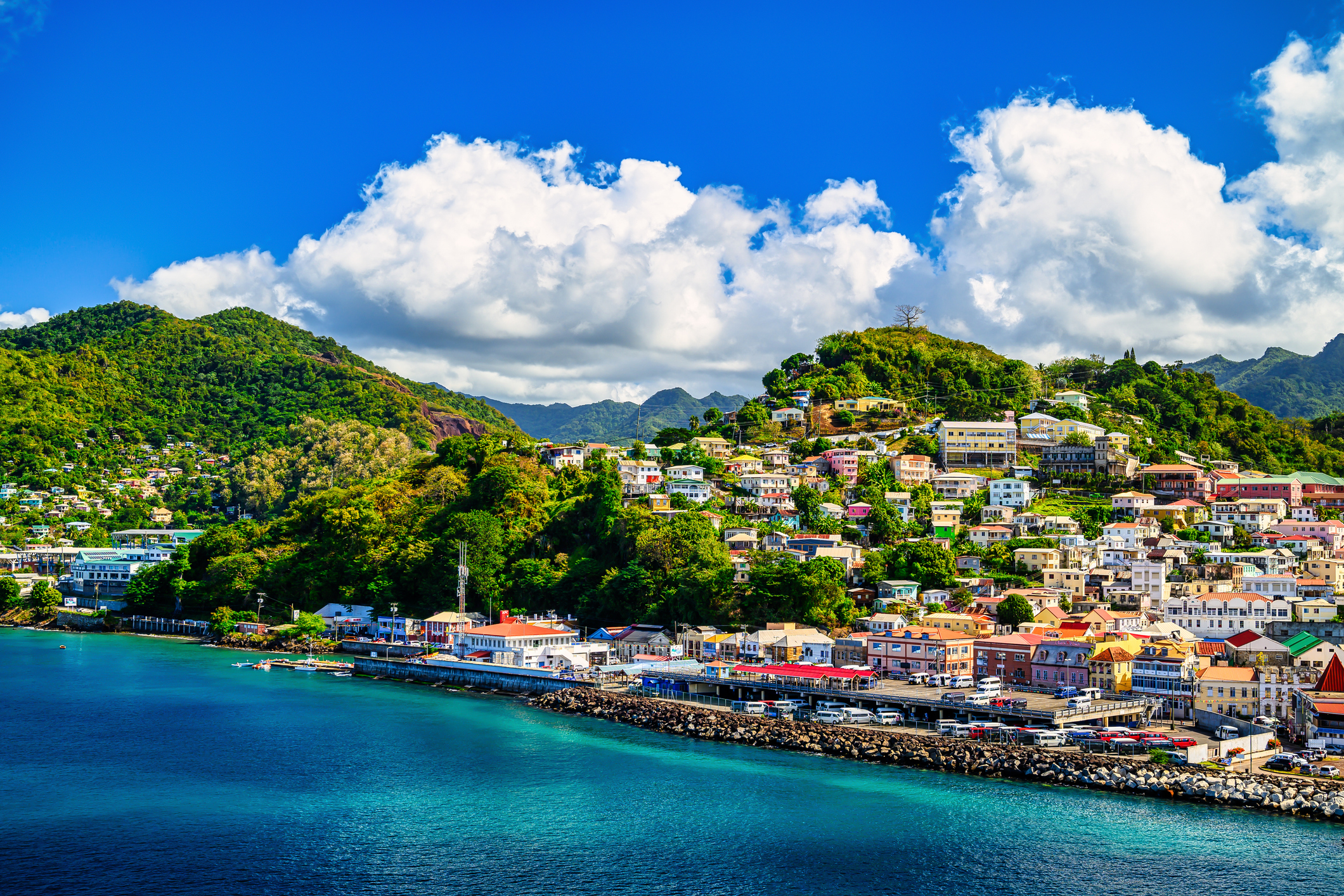 The capital of Grenada set amongst green mountains seen from across vibrant blue water.