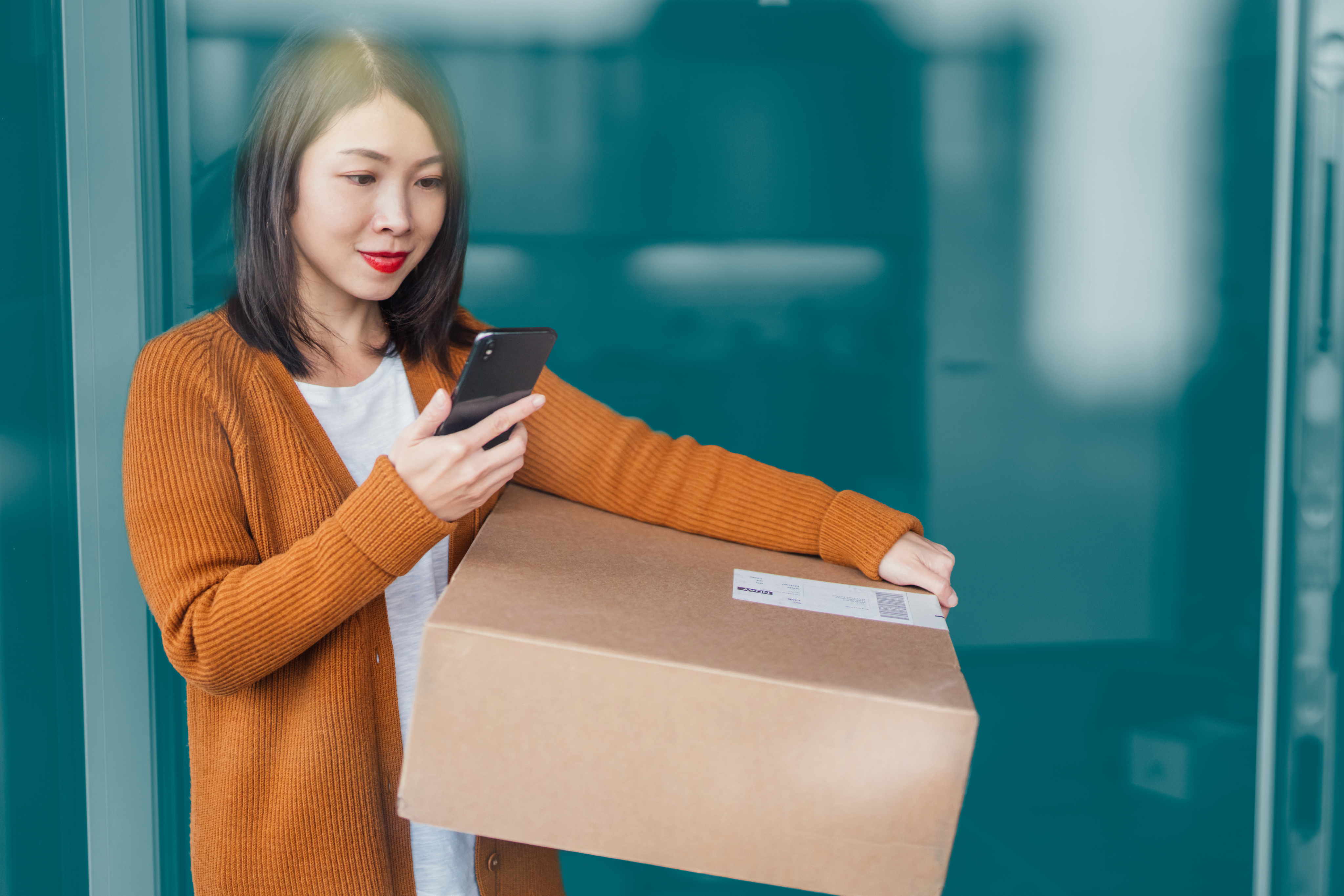 Woman carrying parcel and checking phone with blue background