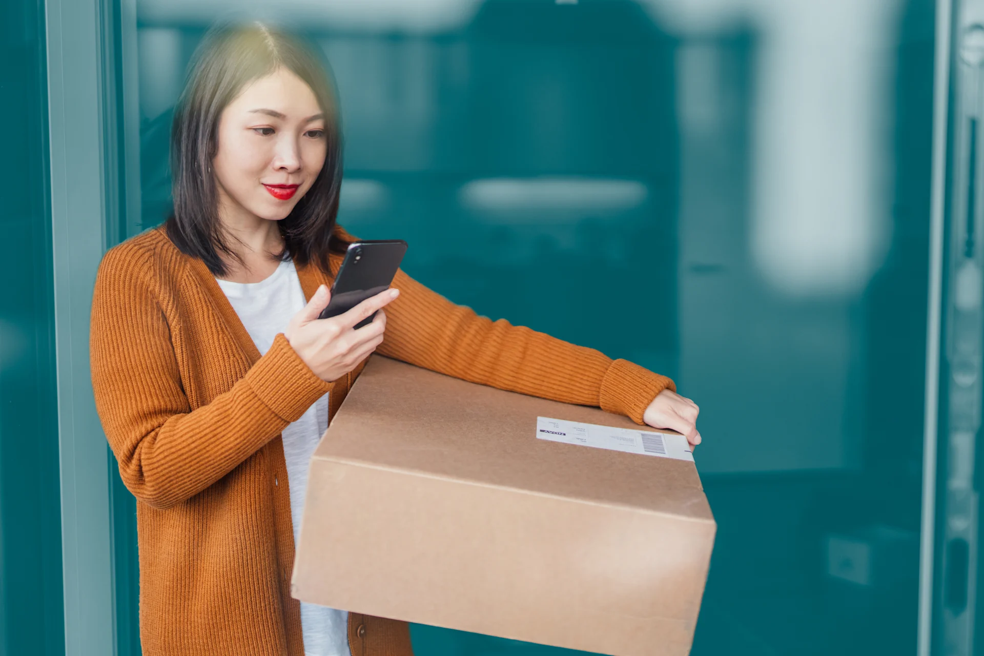 Woman carrying parcel and checking phone with blue background