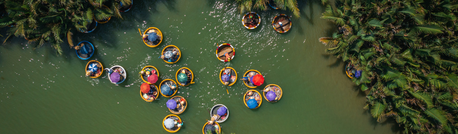 People riding down a river in Vietnam, in small colourful boats with colourful umbrellas.
