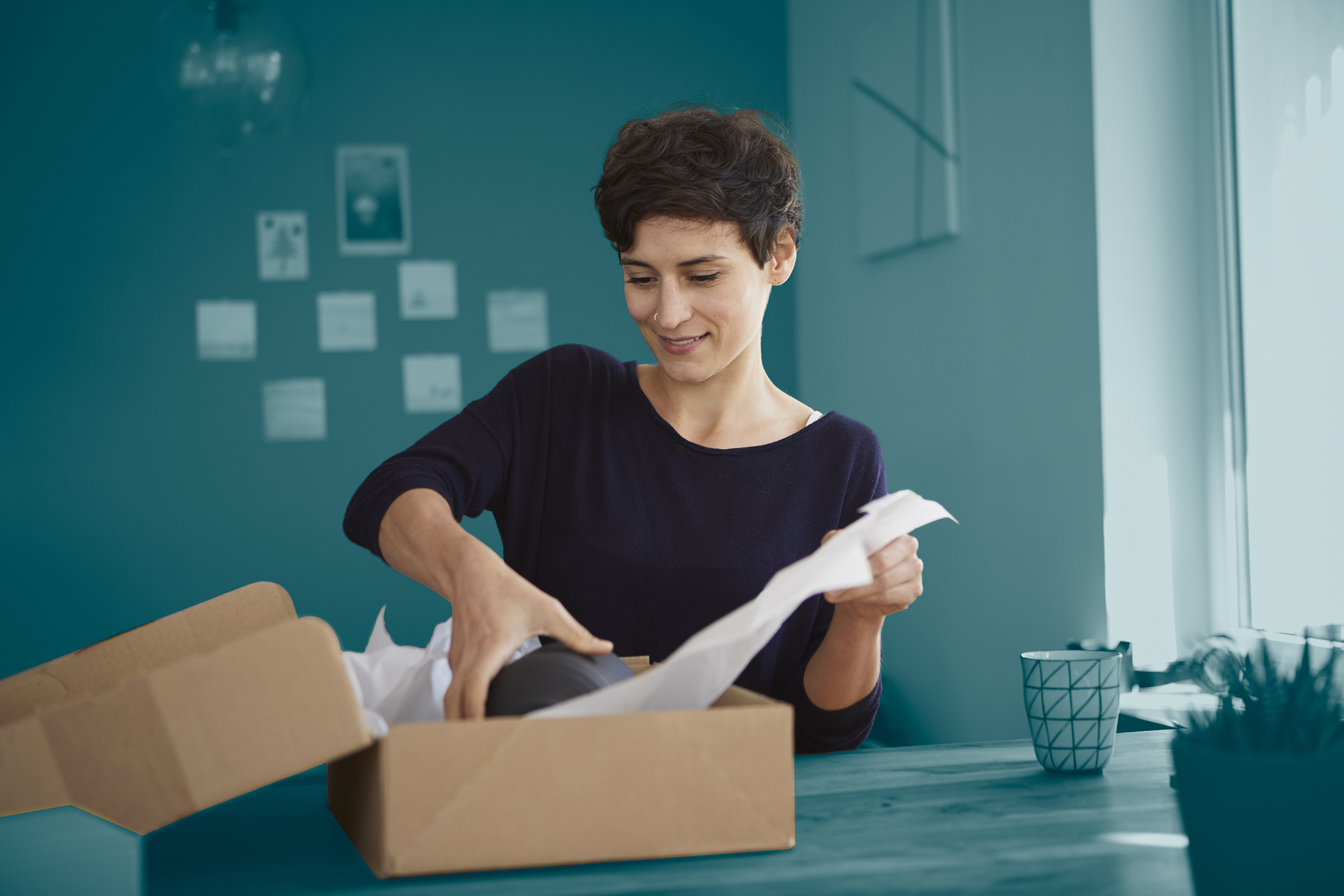 Woman packaging parcel with blue background