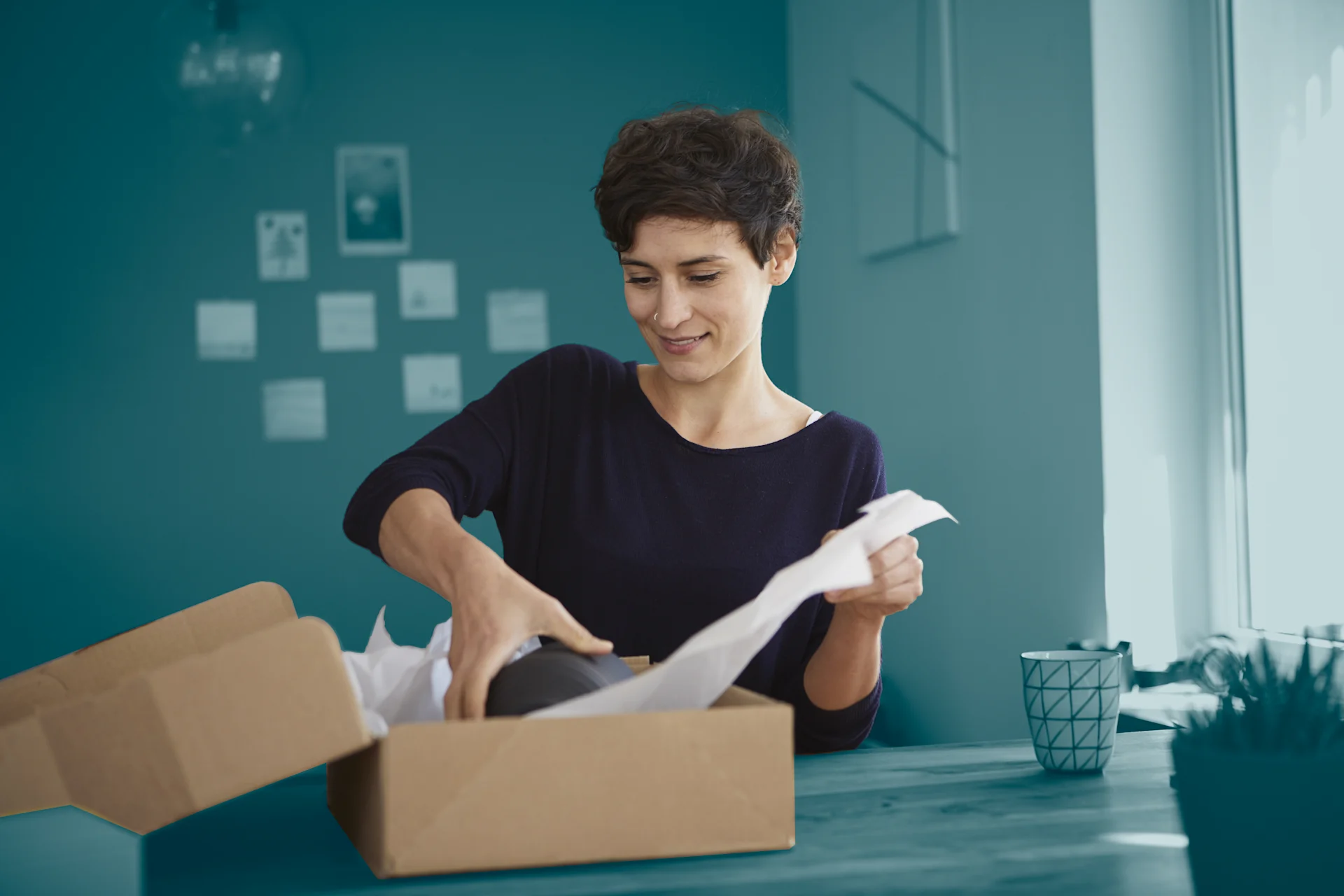 Woman packaging parcel with blue background