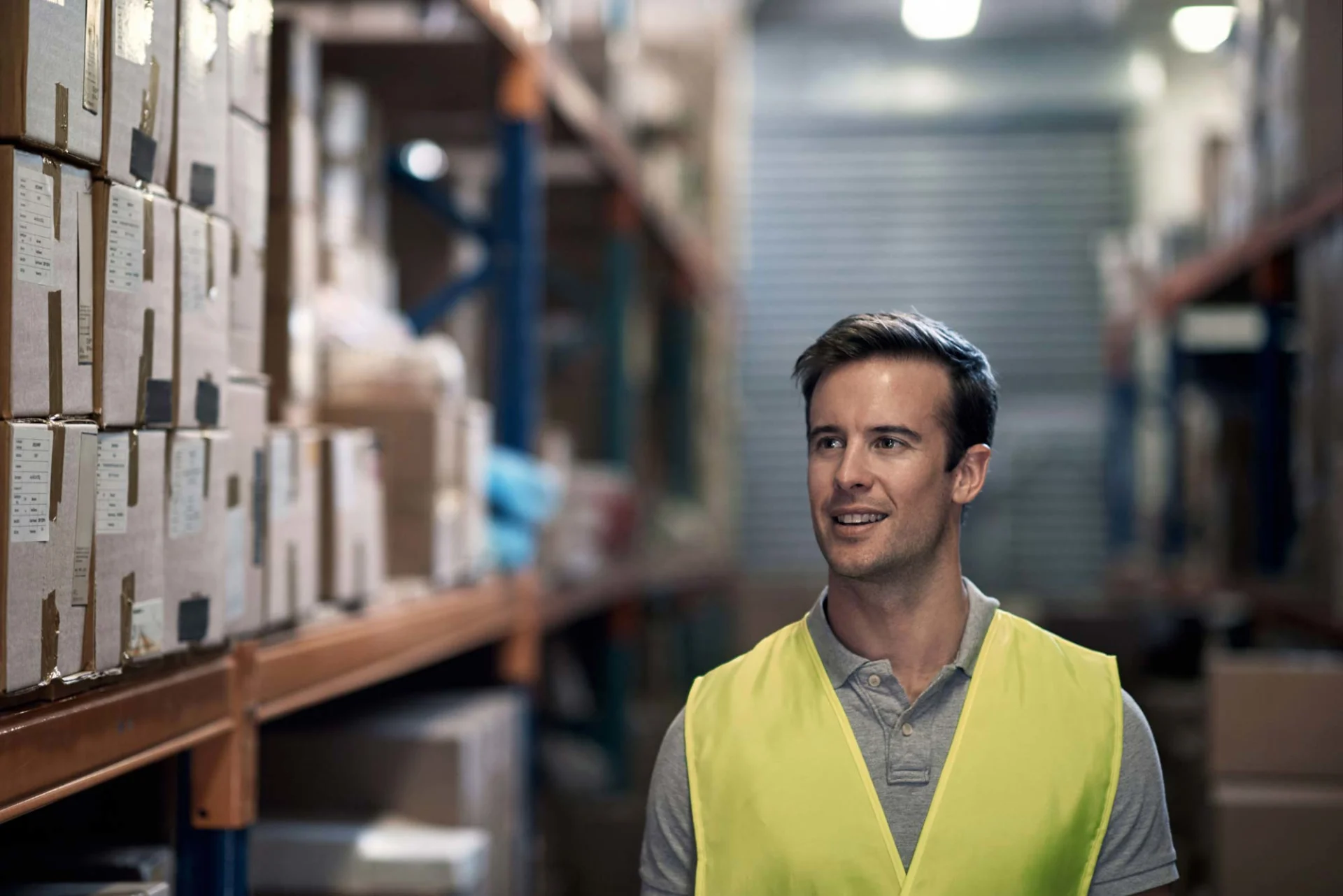 Man smiling in warehouse with parcels