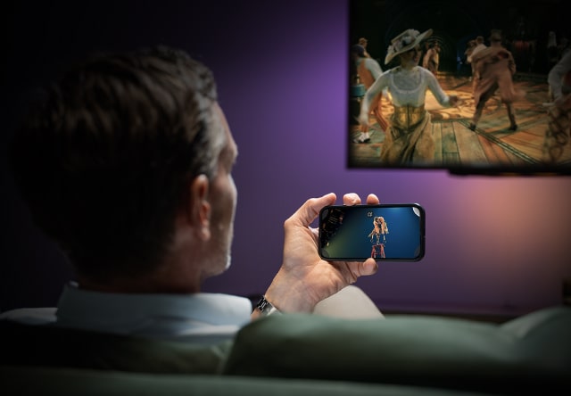 man holding mobile in front of tv