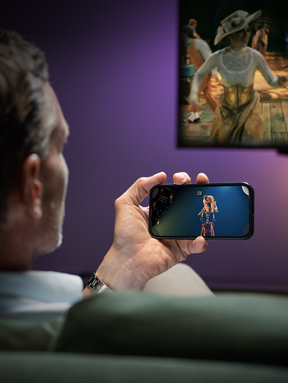 Man holding mobile device in front of TV