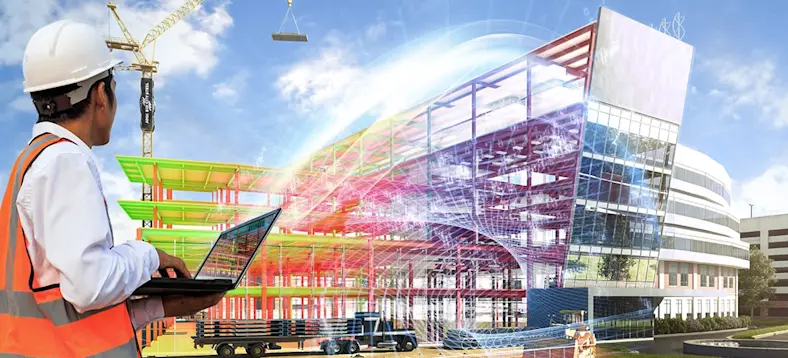 Construction worker on a laptop looking at a building being constructed, with a digital overlay showing the finished building