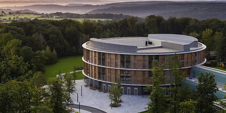 A modern round building is finished in wood panels.